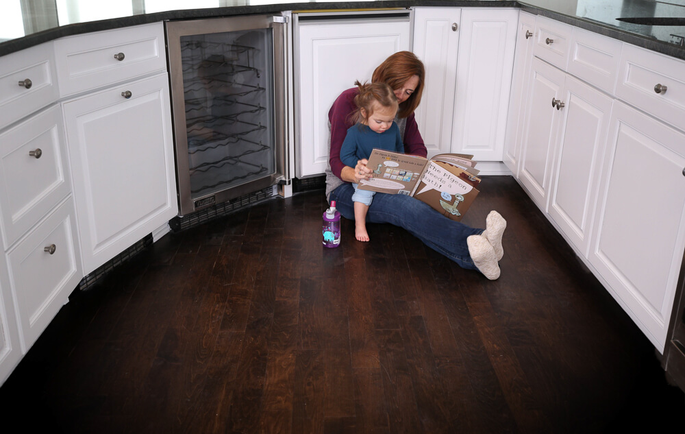 Nhance after picture of remodeled kitchen with mother reading book to her daughter while sitting on the floor