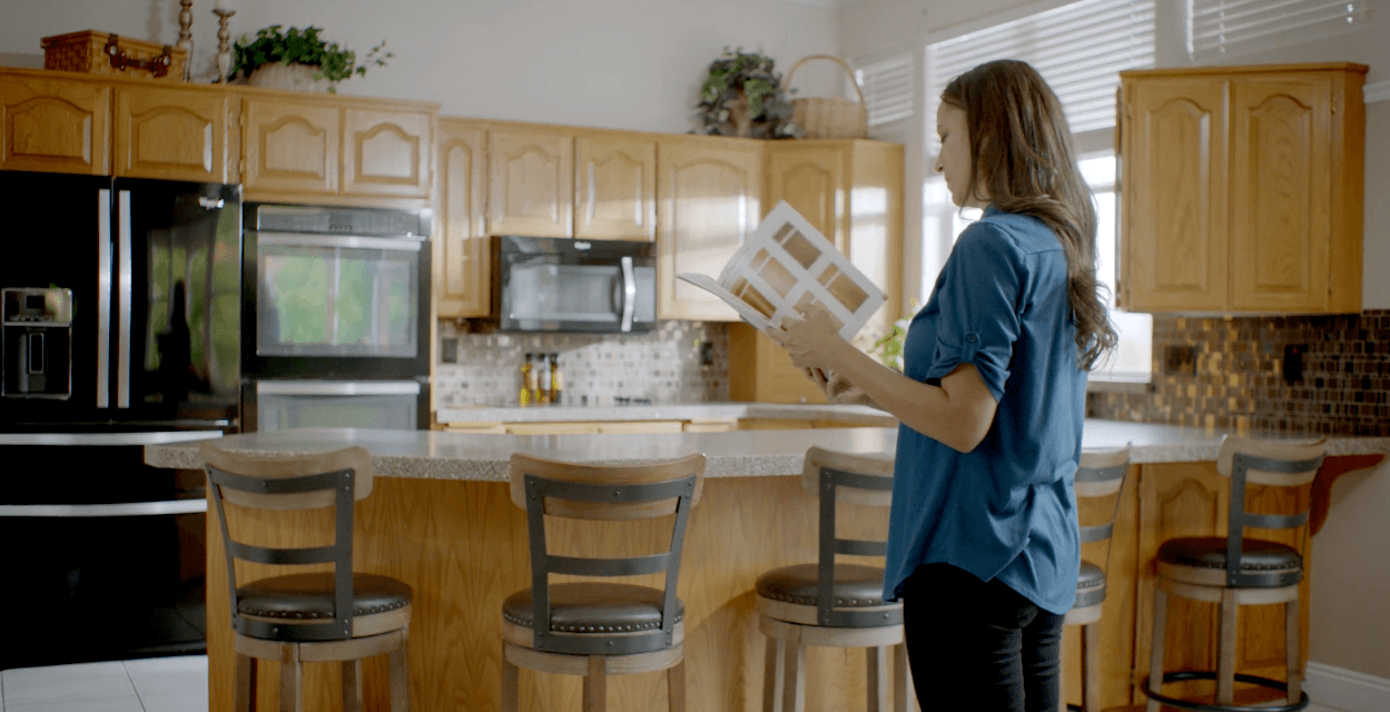 N-Hance franchise customer looks at brochure in her kitchen