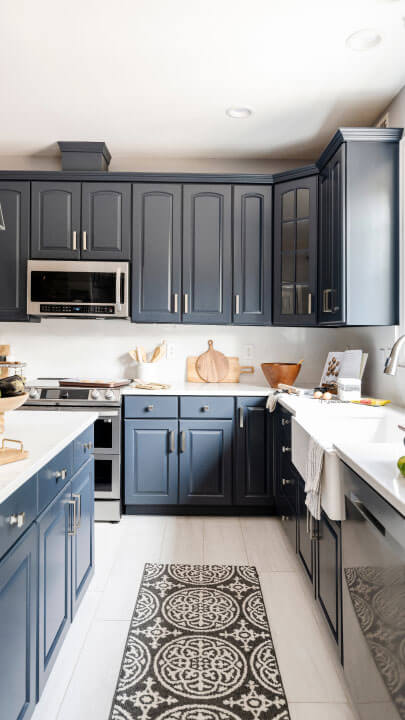 A kitchen with blue cabinets and a white rug that has been updated by a wood refinishing franchise.