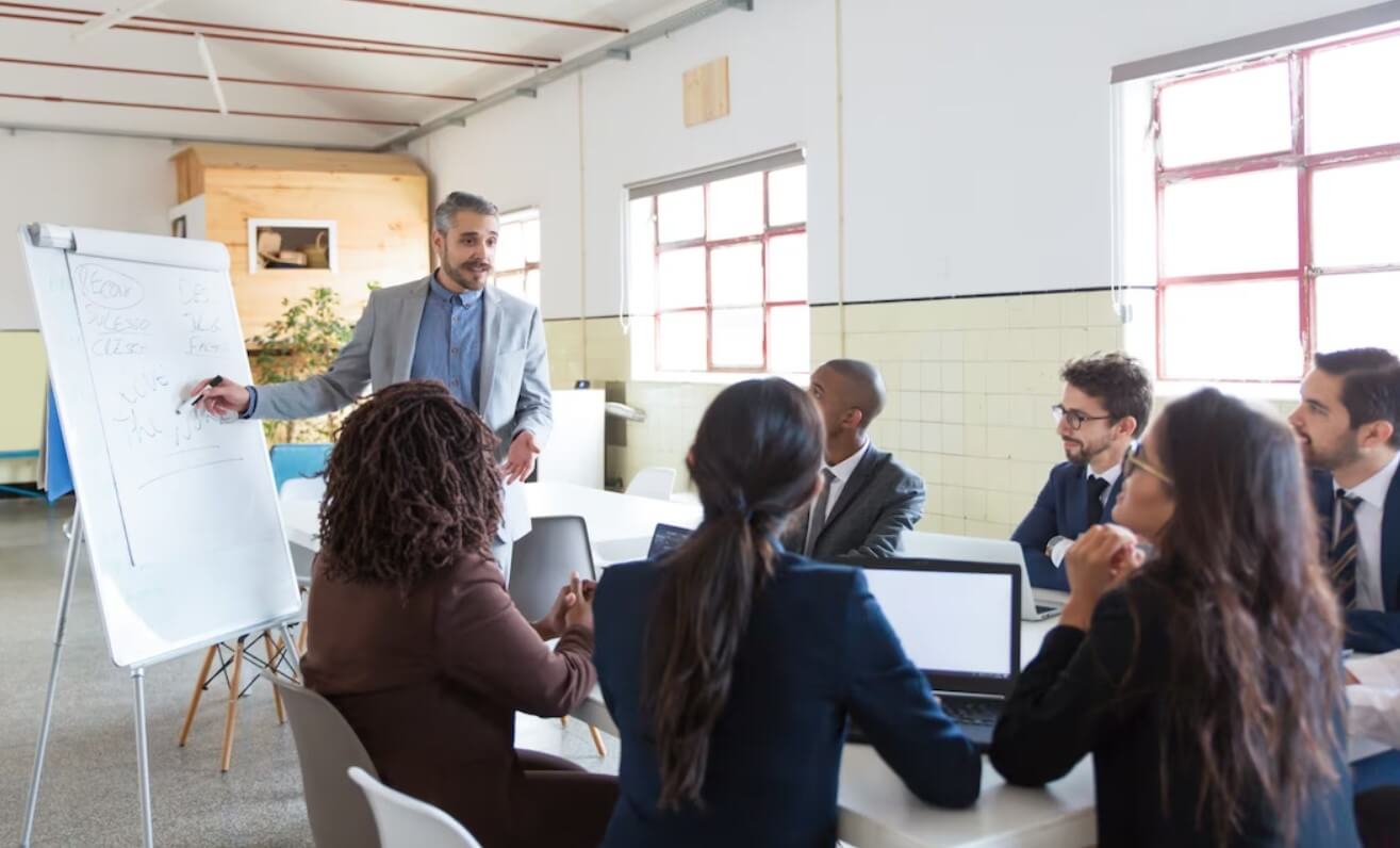 A group of business people sitting around a table in a conference room discussing opportunities with a wood refinishing franchise.